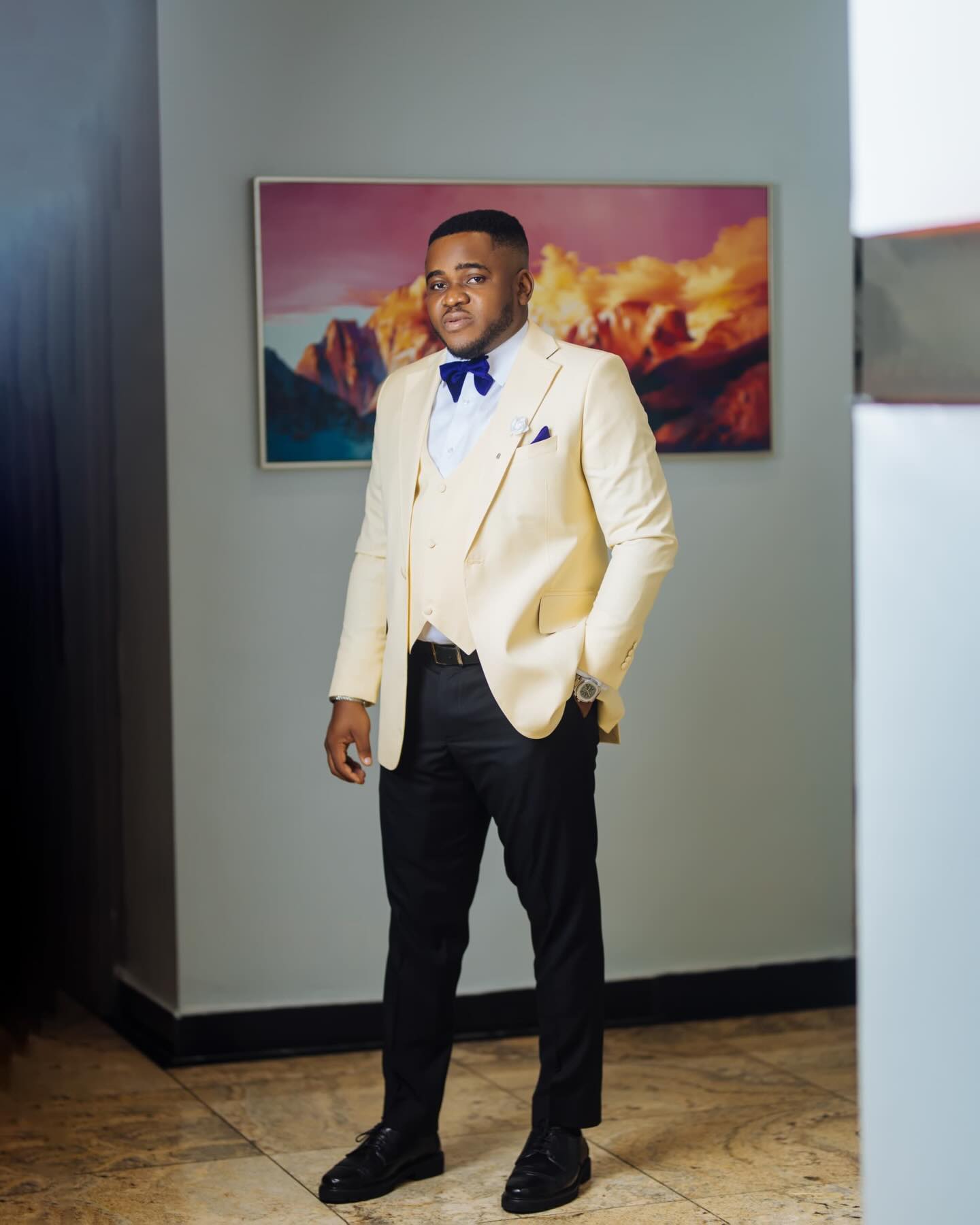 Cream three-piece suit with a cobalt bow — sharp finish.
